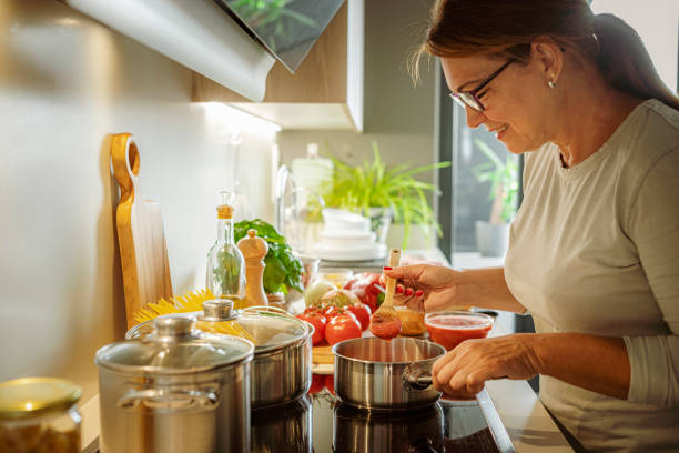 Woman cooking tomato sauce for Italian style spaghetti Woman cooking tomato sauce for perfect Italian pasta recipe large pasta pot stock pictures, royalty-free photos & images