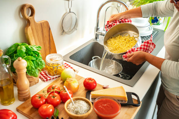 istock Woman draining the water from the spaghetti using a colander 1532952082