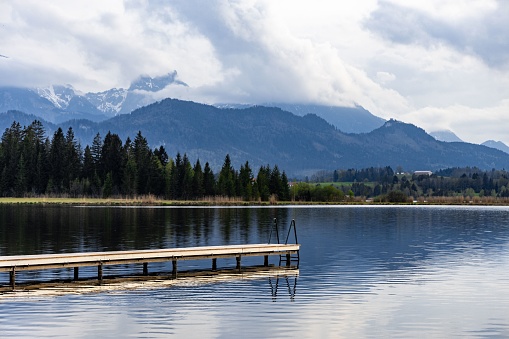 A tranquil landscape featuring an empty dock at a mountain lake in Bavarian Alps, Germany.