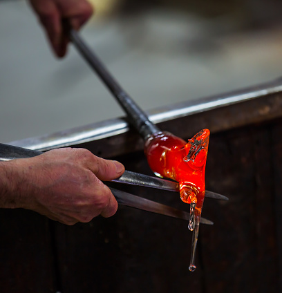 Glass blower at work shaping molten glass, Murano, Venice, Italy (selective focus)