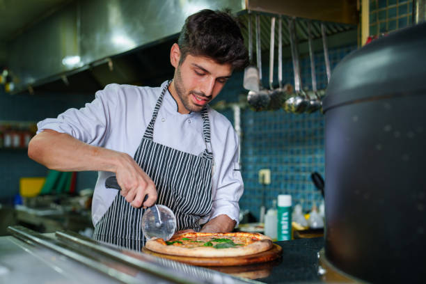 istock Chef preparing pizza in kitchen next to oven 1532978766