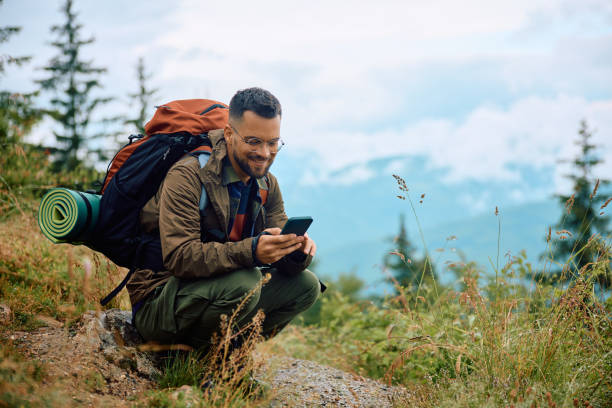 istock Happy backpacker texting on cell phone while hiking in the mountains. 1532979304