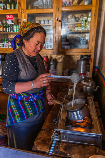 Tibetan woman preparing meal in kitchen, Lo Manthang, Upper Mustang. Mustang region is the former Kingdom of Lo and now part of Nepal,  in the north-central part of that country, bordering the People's Republic of China on the Tibetan plateau between the Nepalese provinces of Dolpo and Manang.