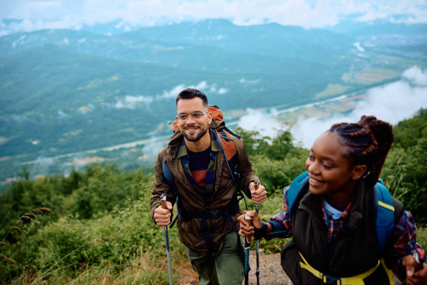 istock Young happy backpackers with hiking poles walking up the hill. 1532981918
