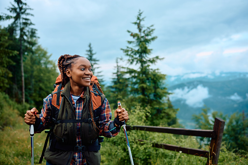 Happy African American woman hiking in nature and looking away. Copy space.