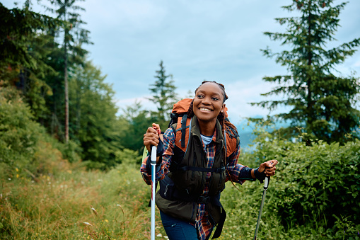 Happy African American female hiker enjoying in a walk in the mountains.