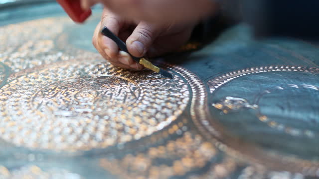 Craftsman doing engravings on a copper metal plate