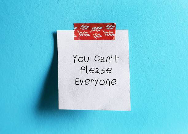 istock White note stick on blue background with handwritten text You Cant Please Everyone - self reminder to stop trying to please everyone and be your authentic self 1533001597