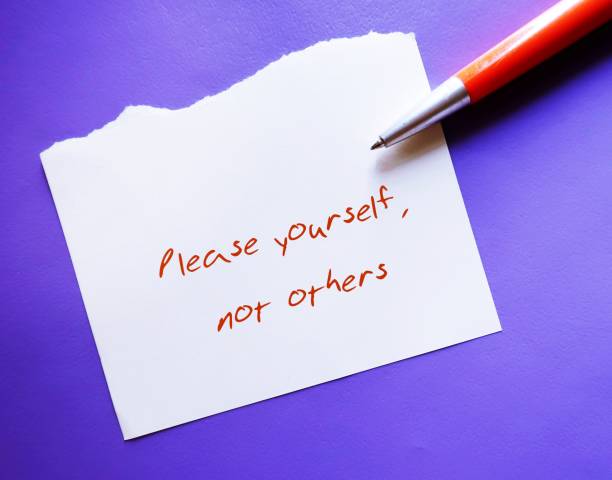 istock Pen and note on purple background with handwritten text PLEASE YOURSELF, NOT OTHERS - concept of stop people-pleasing, approval addiction, stop pleasing others but yourself 1533007935