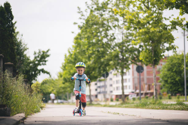 istock Kid with helmet riding push scooter 1533017987
