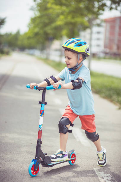istock Kid with helmet riding push scooter 1533026364
