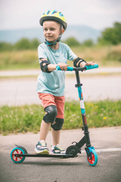 istock Kid with helmet riding push scooter 1533026882