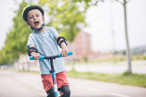 istock Kid with helmet riding push scooter 1533028473