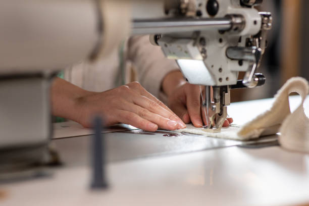 frente a la cámara, la guapa modista usa su máquina de coser profesional para coser un primer plano de un vestido tomando detalles del video - tailor suit textile fashion fotografías e imágenes de stock