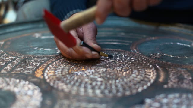 Craftsman doing engravings on a copper metal plate