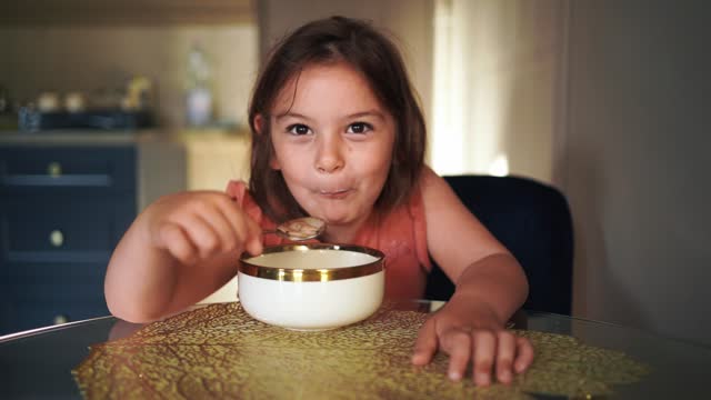 Child girl eating with spoon from the bowl at home. . High quality photo