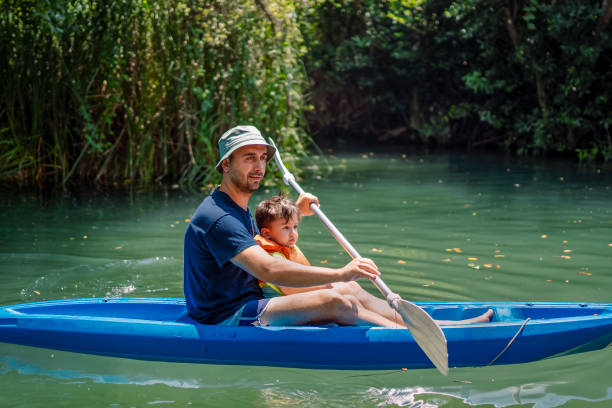 young father and his toddler boy kayaking together - exploration curiosity nature canoeing imagens e fotografias de stock