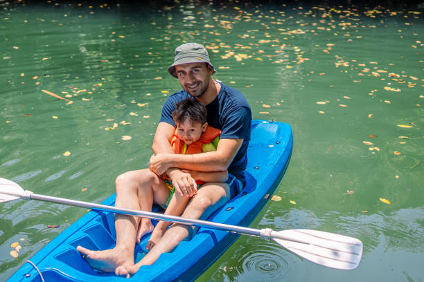 young father and his toddler boy kayaking together - exploration curiosity nature canoeing imagens e fotografias de stock