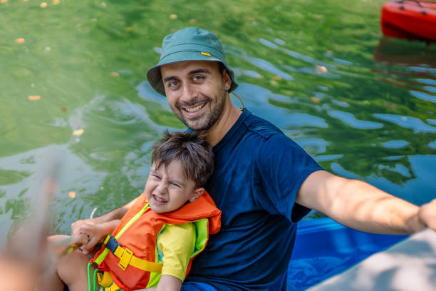 young father and his toddler boy kayaking together - exploration curiosity nature canoeing imagens e fotografias de stock