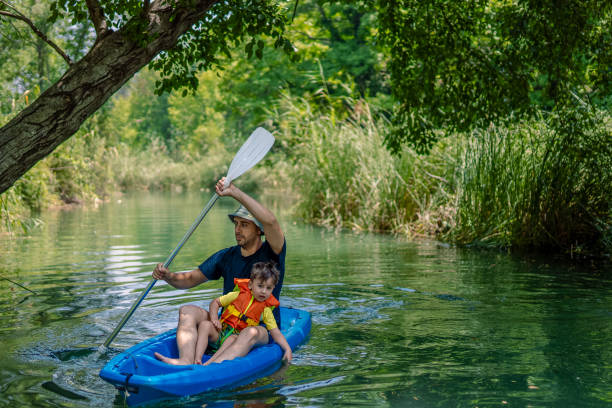 young father and his toddler boy kayaking together - exploration curiosity nature canoeing imagens e fotografias de stock
