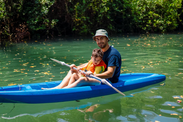 giovane padre e il suo bambino che fanno kayak insieme - exploration curiosity nature canoeing foto e immagini stock