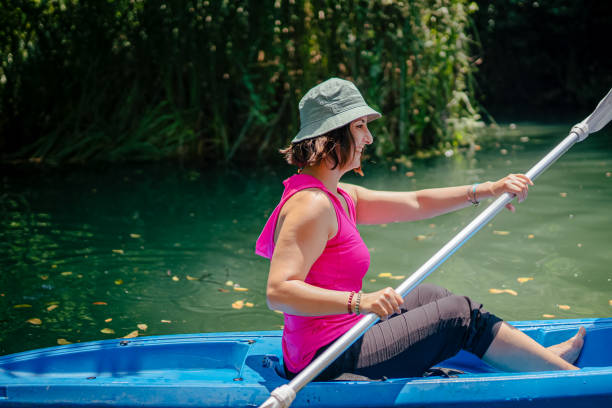 kayak di pagaiata della donna nel fiume e ridere - exploration curiosity nature canoeing foto e immagini stock