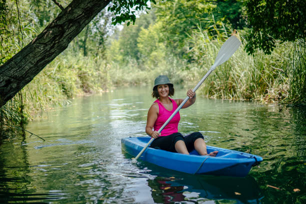 kayak di pagaiata della donna nel fiume e ridere - exploration curiosity nature canoeing foto e immagini stock