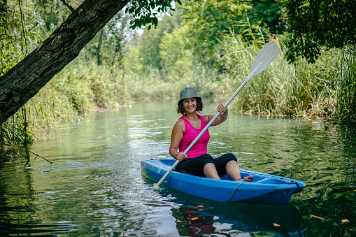 Woman paddling kayak in river and laughing