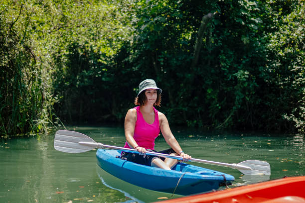 kayak di pagaiata della donna nel fiume e ridere - exploration curiosity nature canoeing foto e immagini stock