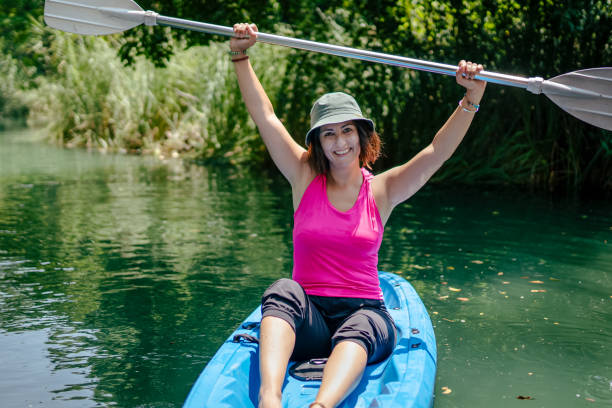 woman paddling kayak in river and laughing - exploration curiosity nature canoeing imagens e fotografias de stock