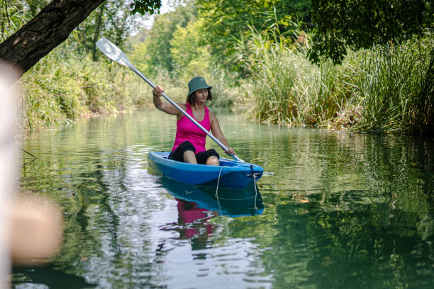 kayak di pagaiata della donna nel fiume - exploration curiosity nature canoeing foto e immagini stock