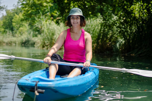 kayak di pagaiata della donna nel fiume e ridere - exploration curiosity nature canoeing foto e immagini stock