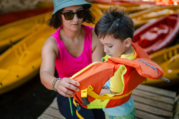 madre che prepara il suo figlio per il kayak - exploration curiosity nature canoeing foto e immagini stock