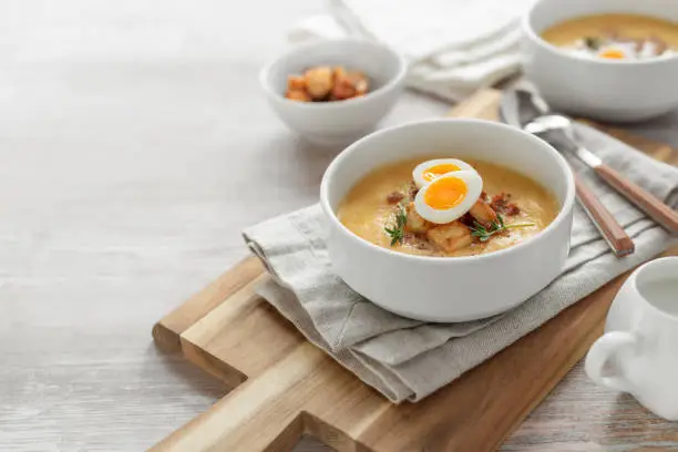 Creamy vegetable soup garnished with bacon, boiled eggs and fresh thyme