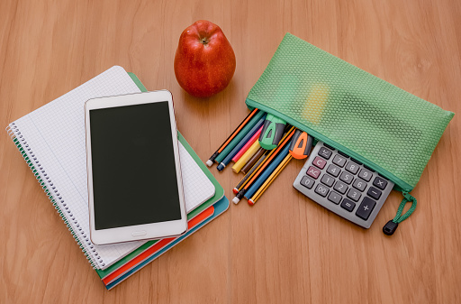 Group of school supplies and notebooks on a brown desk, student accessories - copy space for text on digital tablet, back to school concept