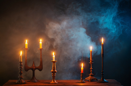 burning candles in vintage candlesticks on dark background