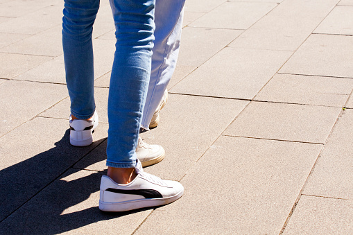 Two people , young couple wearing jeans walking together  in the street in  Santiago de Compostela  , A Coruna, Galicia, Spain.