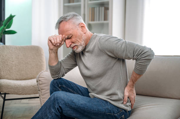 istock Old man sitting on couch and feeling sudden back pain 1533312600