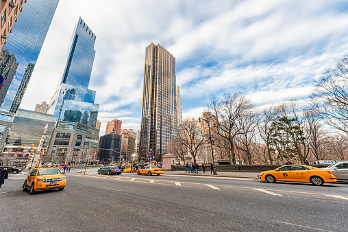 New York, USA - Nov 13th, 2014: Yellow taxi cabs driving through Central Park with skyscraper background in the fall