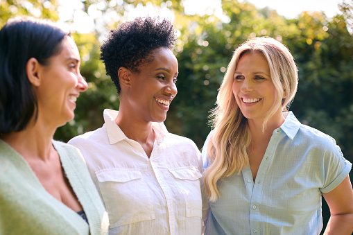 Three Smiling Mature Female Friends Outdoors Spending Time In Countryside Together