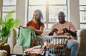 A husband and wife sits folding laundry. Stock photo