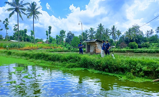 Lampung, Indonesia - May, 2023 : a group of teams is covering the news about cultivating catfish in fish ponds.
