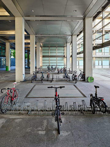 University campus bicycle parking racks next to modern architecture buildings, no people.