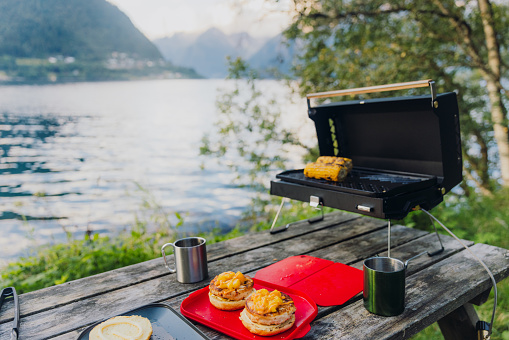 Grilling burgers and corn on grill stove by the sea during scenic sunset with Mountain View