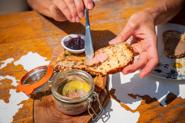 istock Spreading goose pate with table knife on a bread slice at the wooden table 1533420127