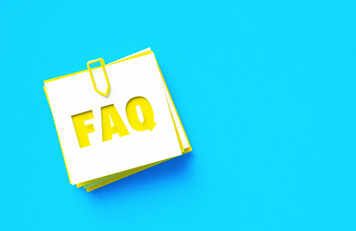 FAQ written cut out yellow adhesive notes sitting on blue background. Horizontal composition with copy space.