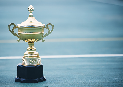 Sports, award and trophy on the floor with no people at court for success, winner or achievement. Prize, victory and sport reward on a ground at an empty stadium for sport, champion and competition