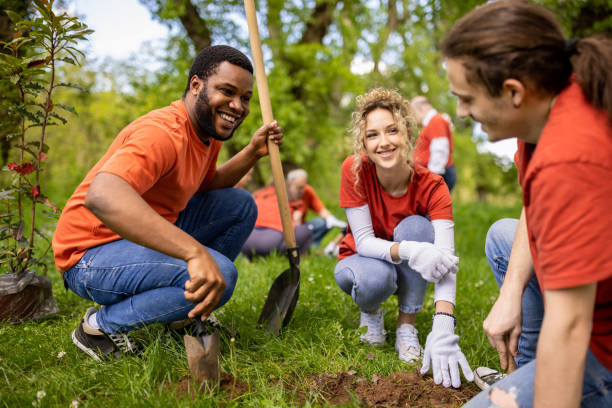Group of young people digging a hole for planting a tree