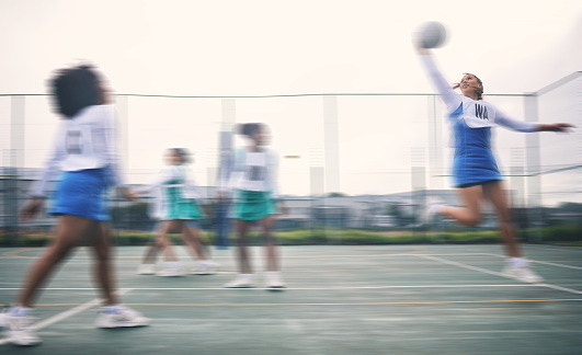 Sports, netball and fitness jump by women at outdoor court for training, workout and practice. Exercise, students and girl team with ball for competition, speed and performance while active at field