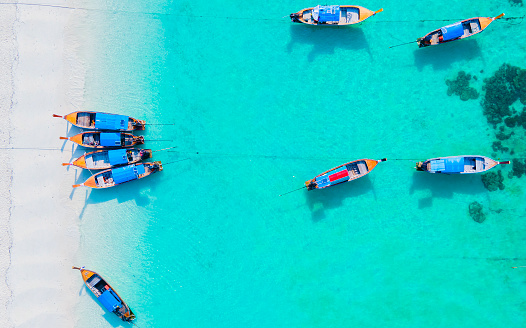 colorful Longtail boats in the blue ocean of Koh Lipe Island Southern Thailand with turqouse colored ocean and white sandy beach at Ko Lipe.
